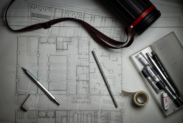 A drafting compass sitting on a clear architectural blueprint