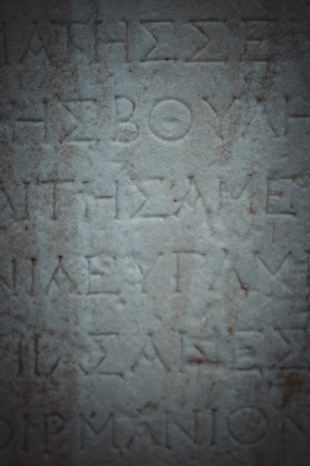A detailed close-up of ancient, weathered characters chiseled into a rough stone surface